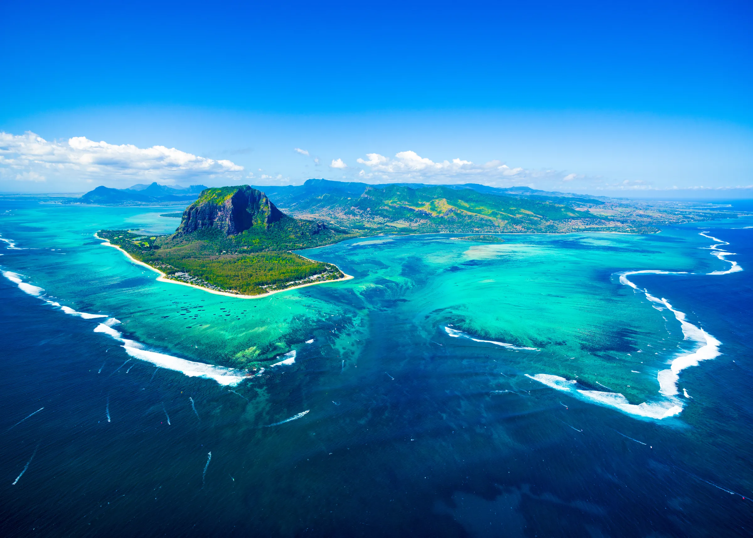 Tropical lagoon in Mauritius with anchored boats, palm-fringed beach, and mountain backdrop—Island Lilly’s signature blend of serenity, culture, and barefoot luxury