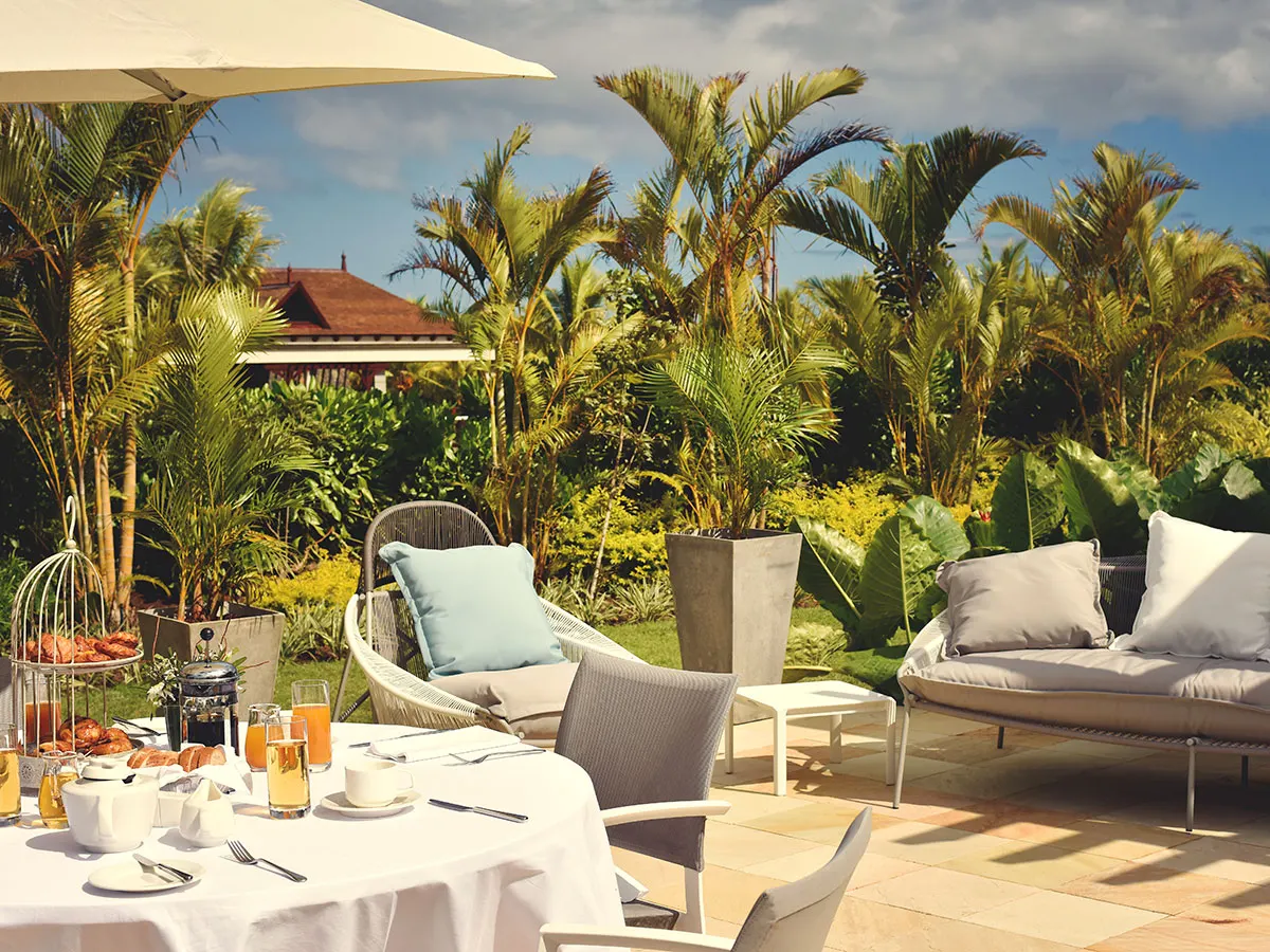 Boats floating near lush green hills and thatched-roof resort in Mauritius—Island Lilly’s curated leisure and exploration experiences