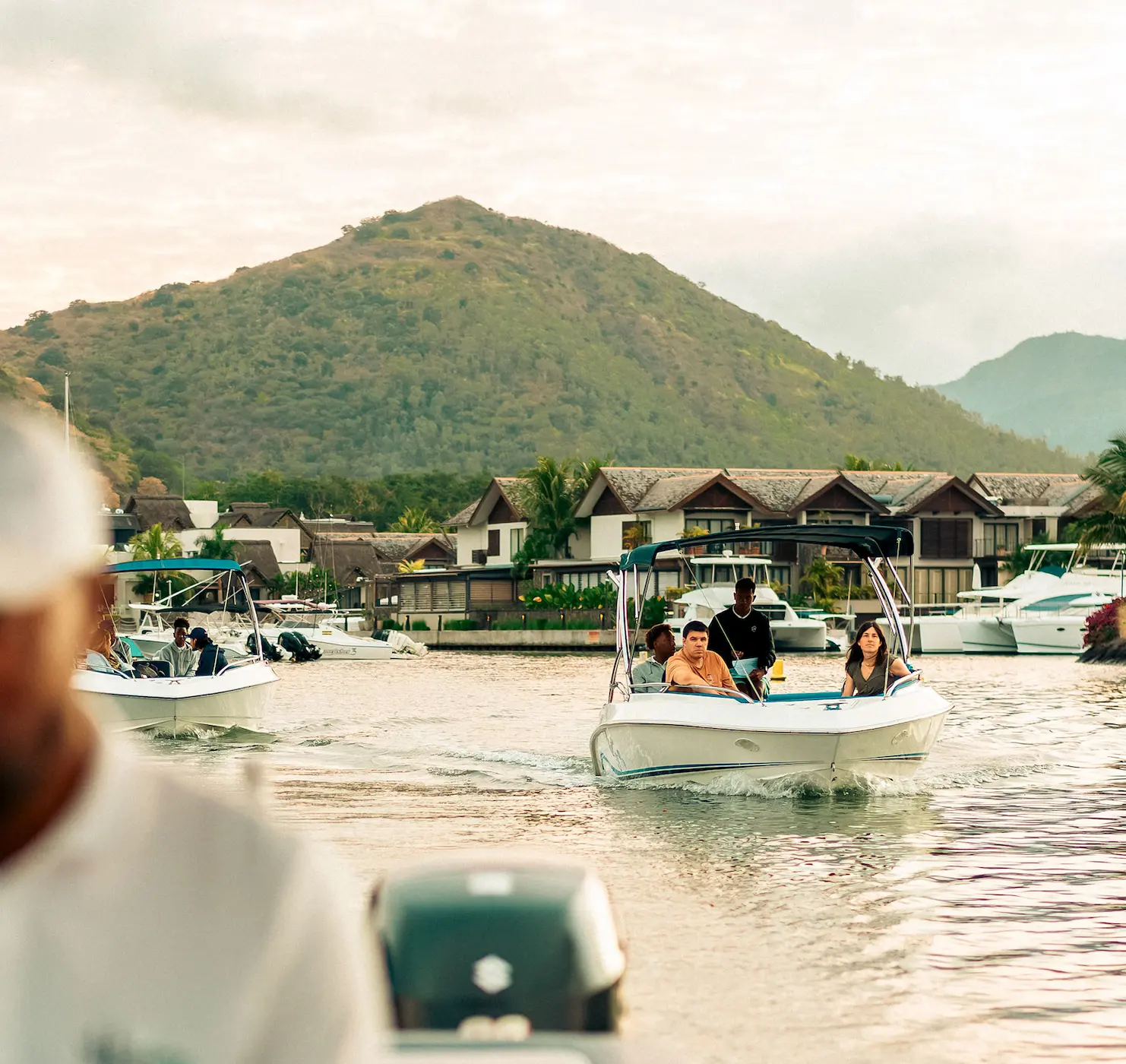 Boats floating near lush green hills and thatched-roof resort in Mauritius—Island Lilly’s curated leisure and exploration experiences