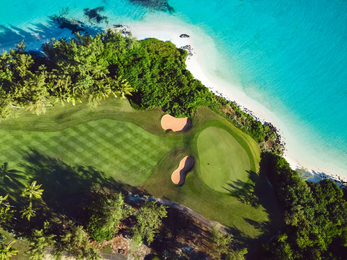 Boats floating near lush green hills and thatched-roof resort in Mauritius—Island Lilly’s curated leisure and exploration experiences