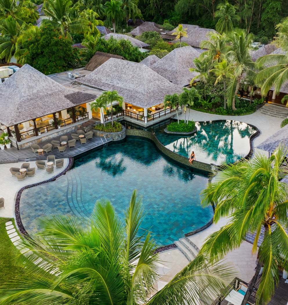 Aerial view of a resort and its lagoon pool among palms at Le Morne, Mauritius.