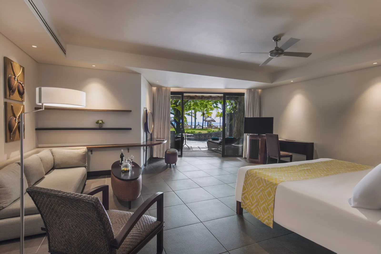 Resort pool with a thatched roof pool bar, cream parasols and loungers, and the lagoon behind
