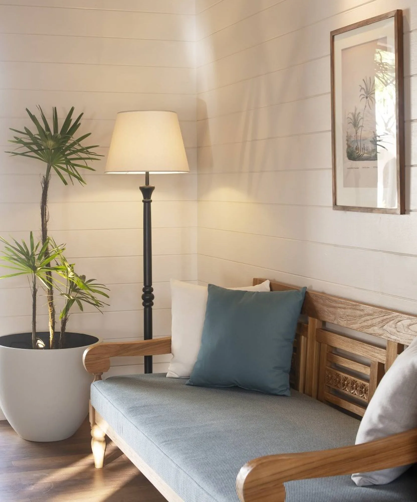 Hotel suite with a wooden floor and green armchair, opening onto a balcony above the sea