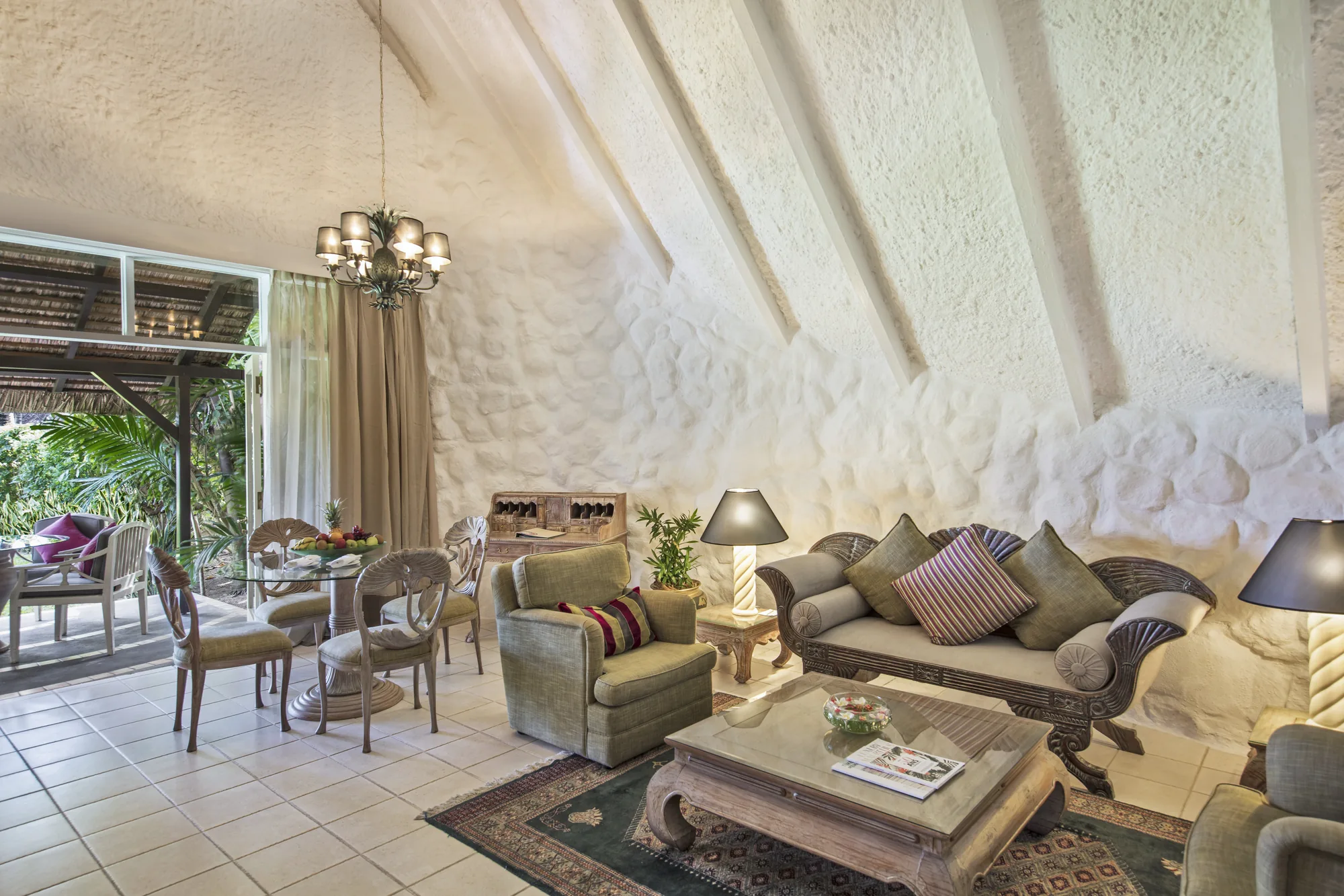 Hotel suite with a wooden floor and green armchair, opening onto a balcony above the sea