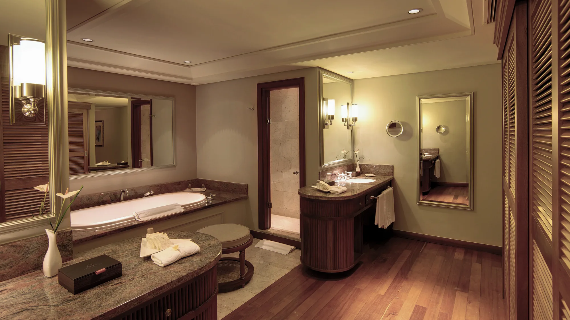 Hotel suite with a wooden floor and green armchair, opening onto a balcony above the sea