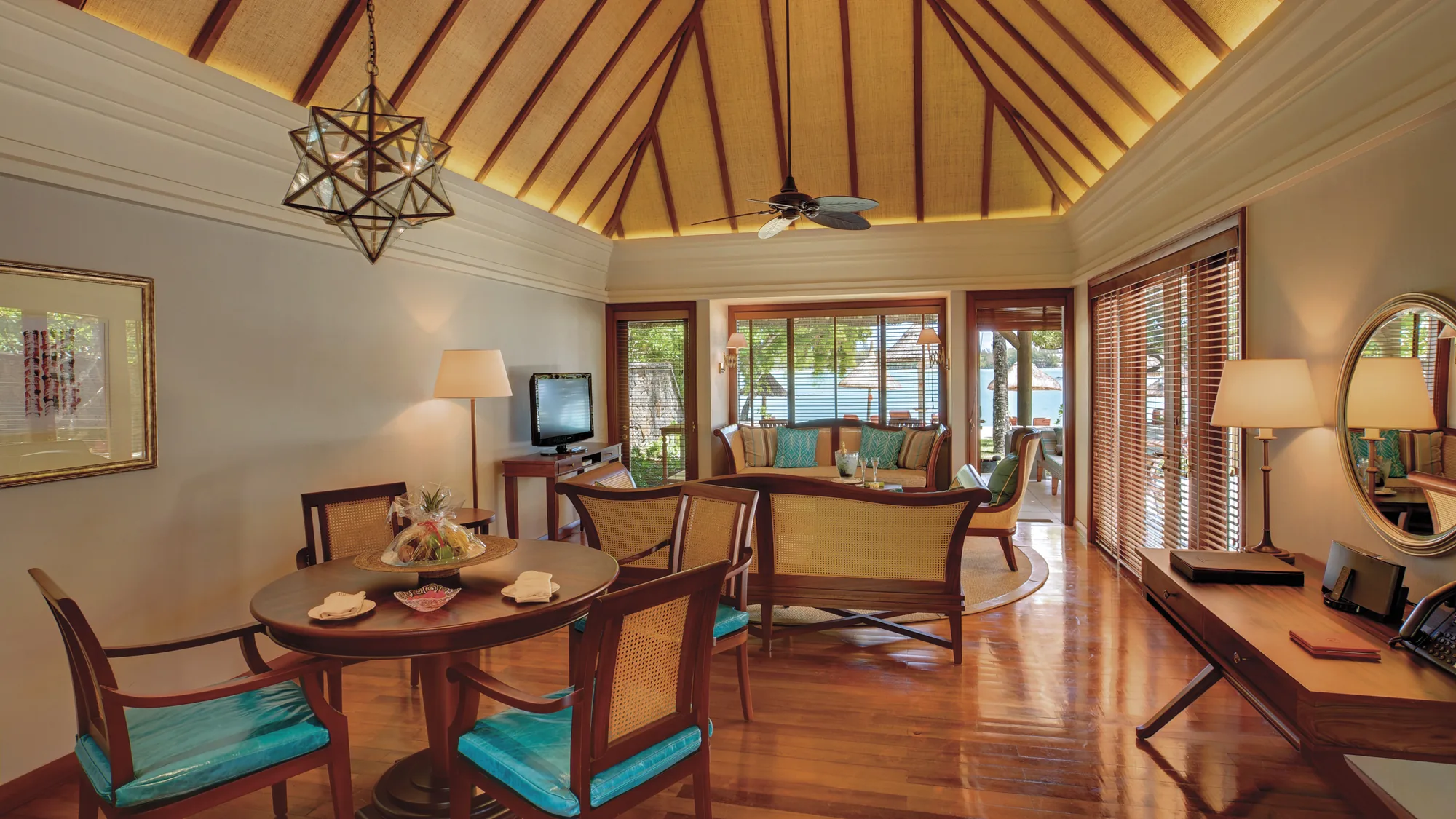 Resort pool with a thatched roof pool bar, cream parasols and loungers, and the lagoon behind