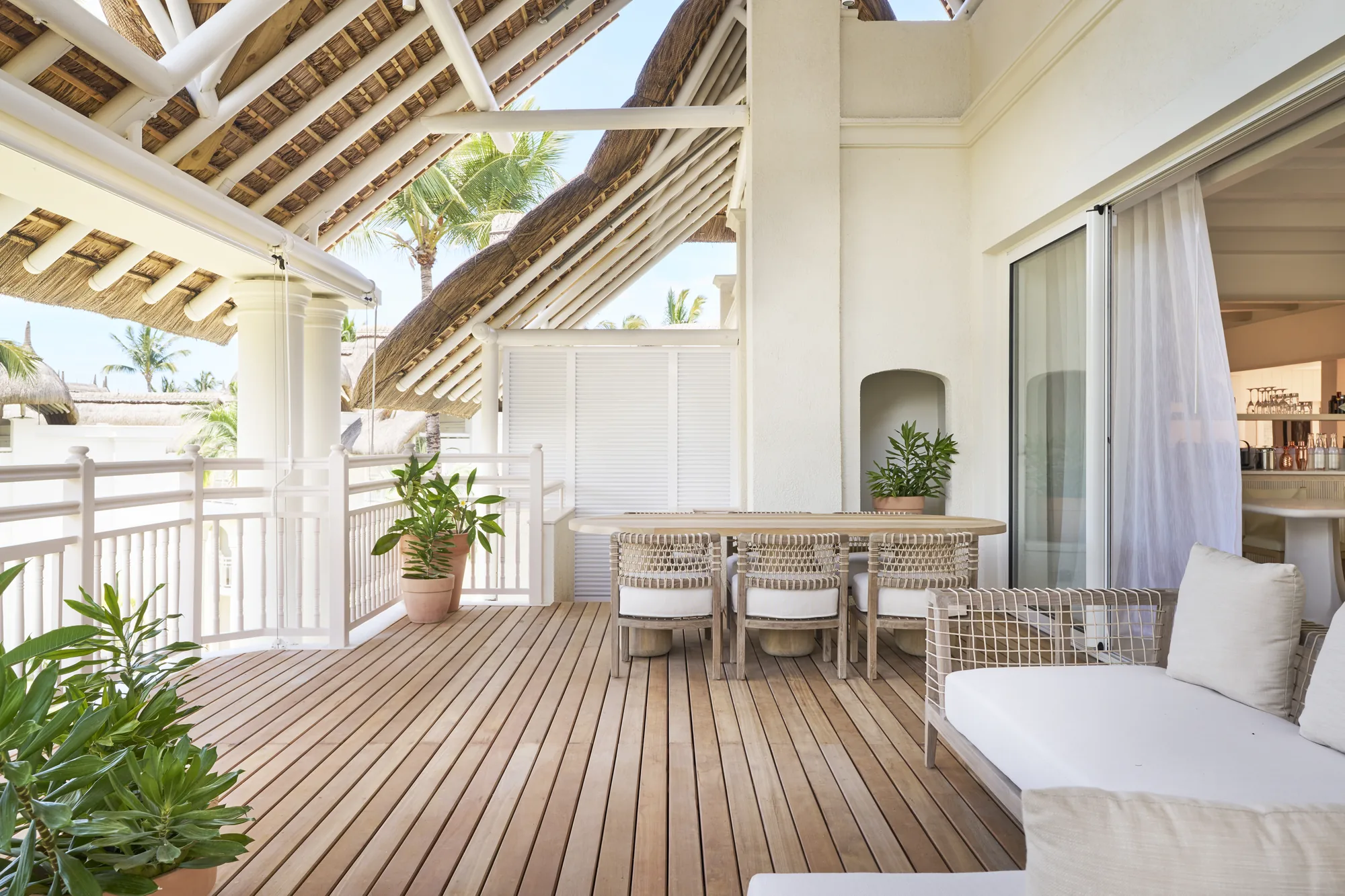 Resort pool with a thatched roof pool bar, cream parasols and loungers, and the lagoon behind