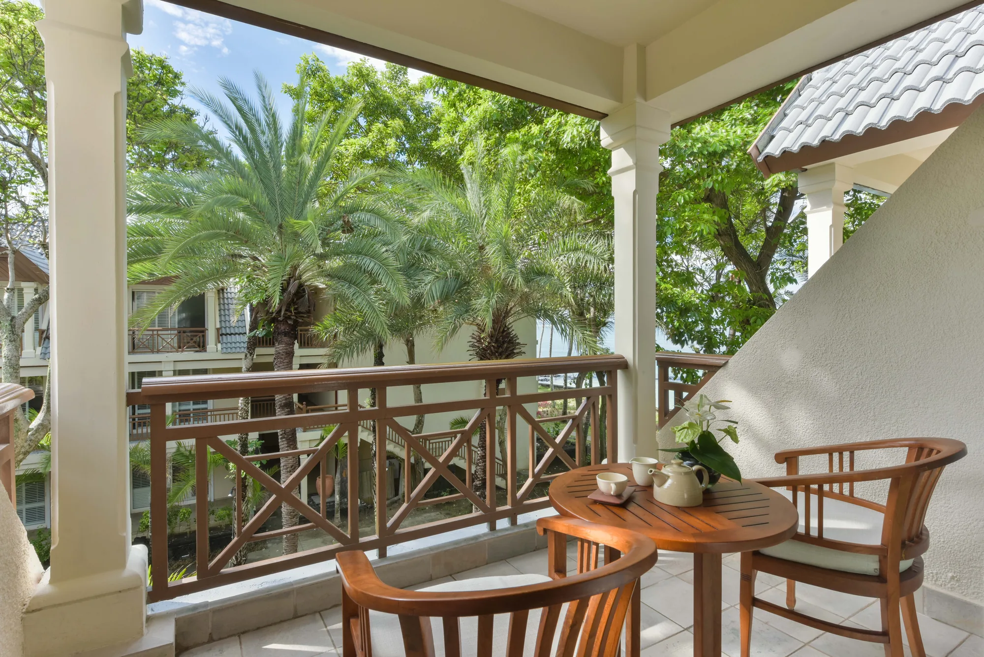 Resort pool with a thatched roof pool bar, cream parasols and loungers, and the lagoon behind
