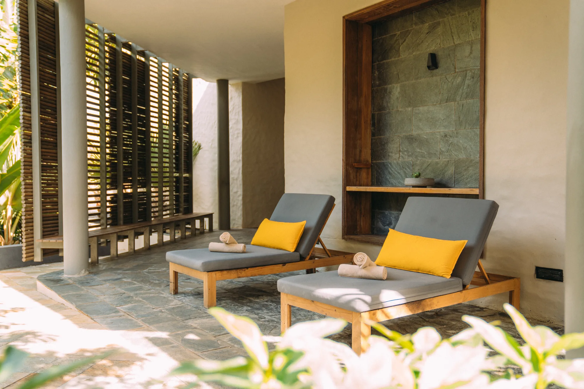 Hotel suite with a wooden floor and green armchair, opening onto a balcony above the sea