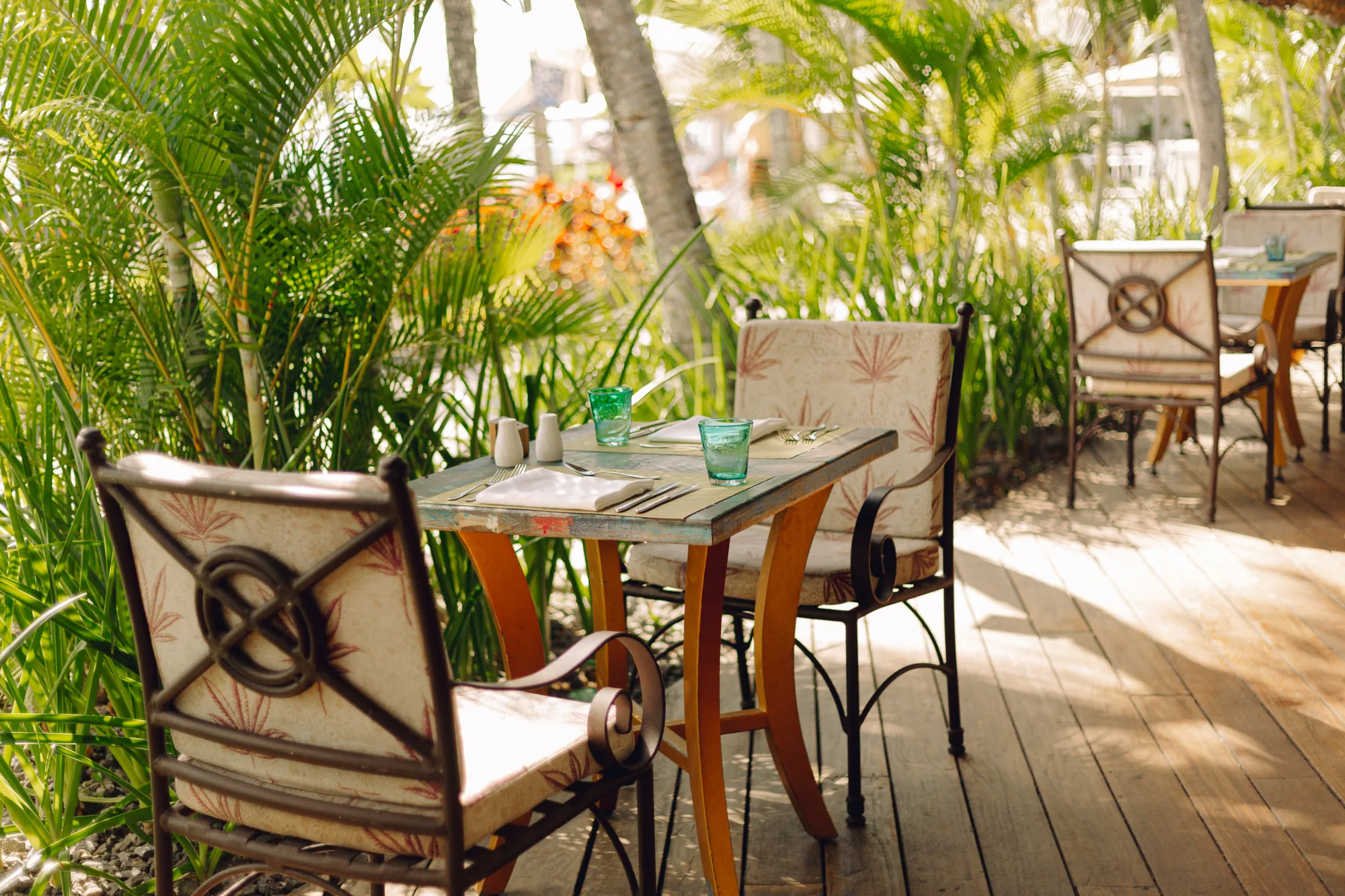 Resort pool with a thatched roof pool bar, cream parasols and loungers, and the lagoon behind
