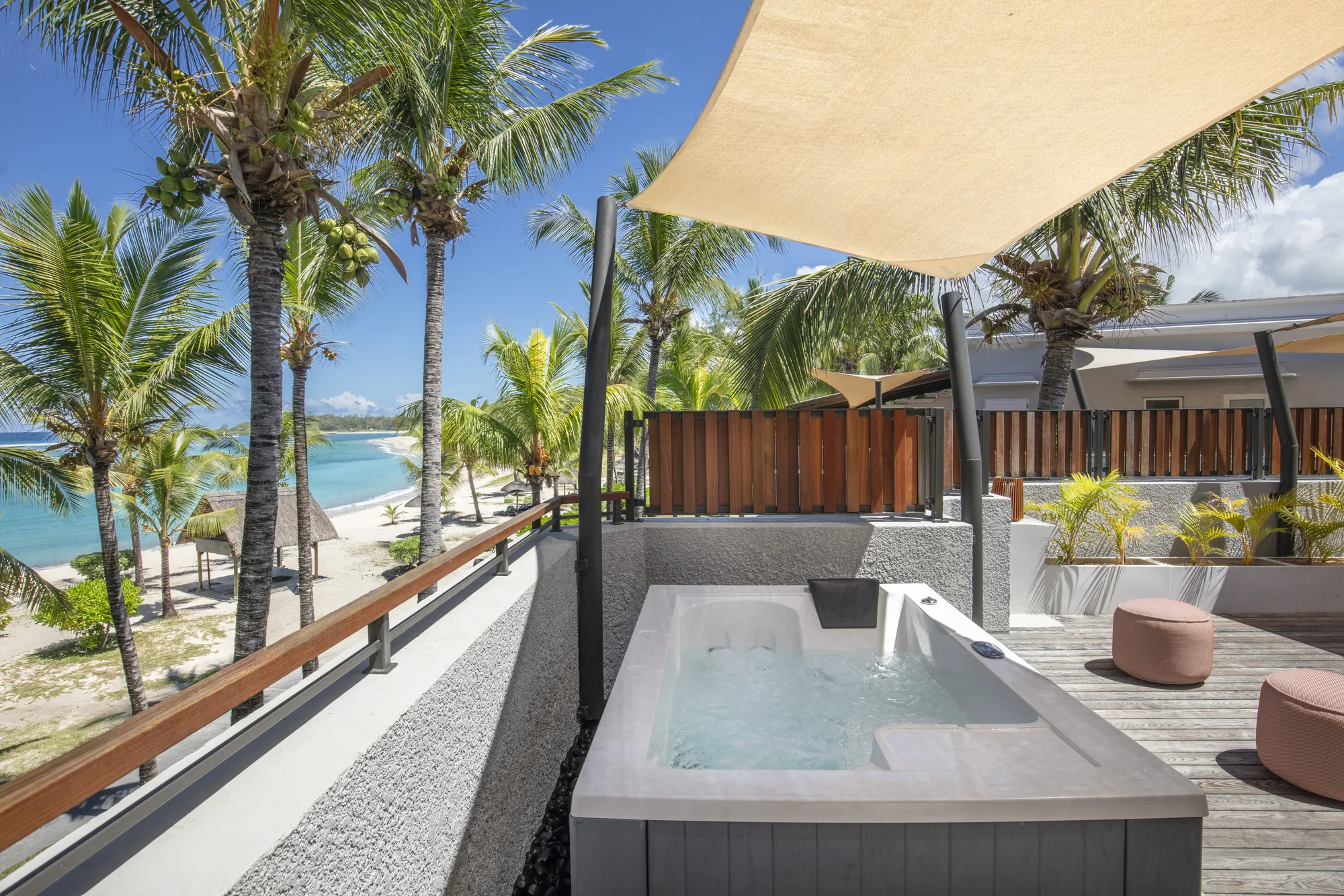 Hotel suite with a wooden floor and green armchair, opening onto a balcony above the sea