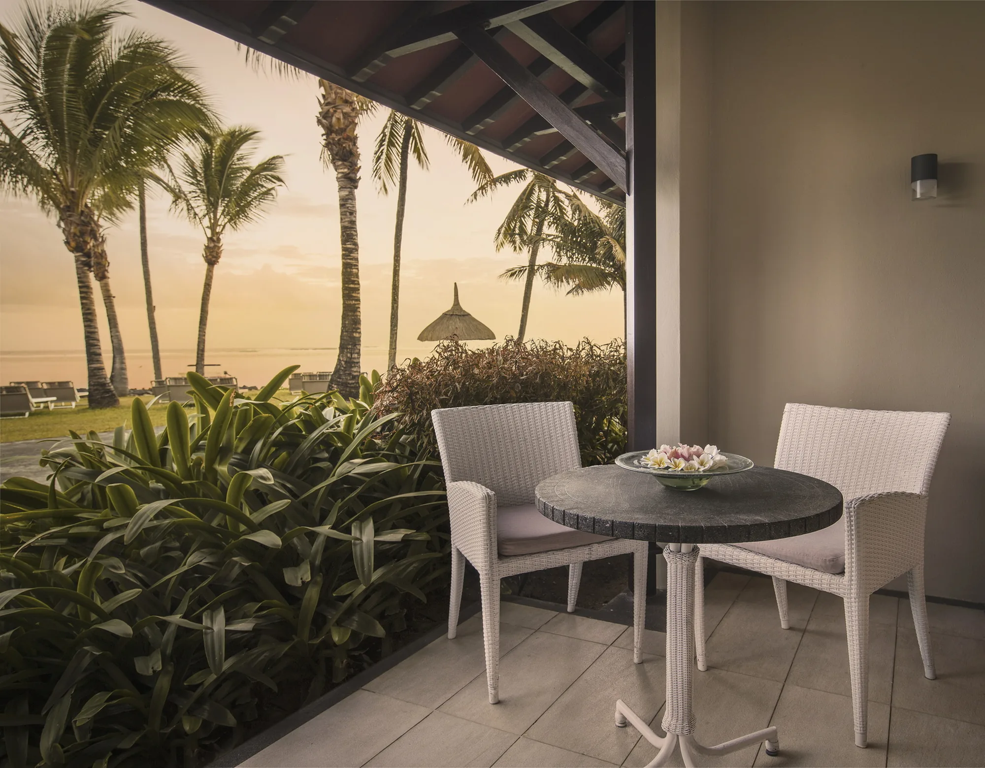 Hotel suite with a wooden floor and green armchair, opening onto a balcony above the sea