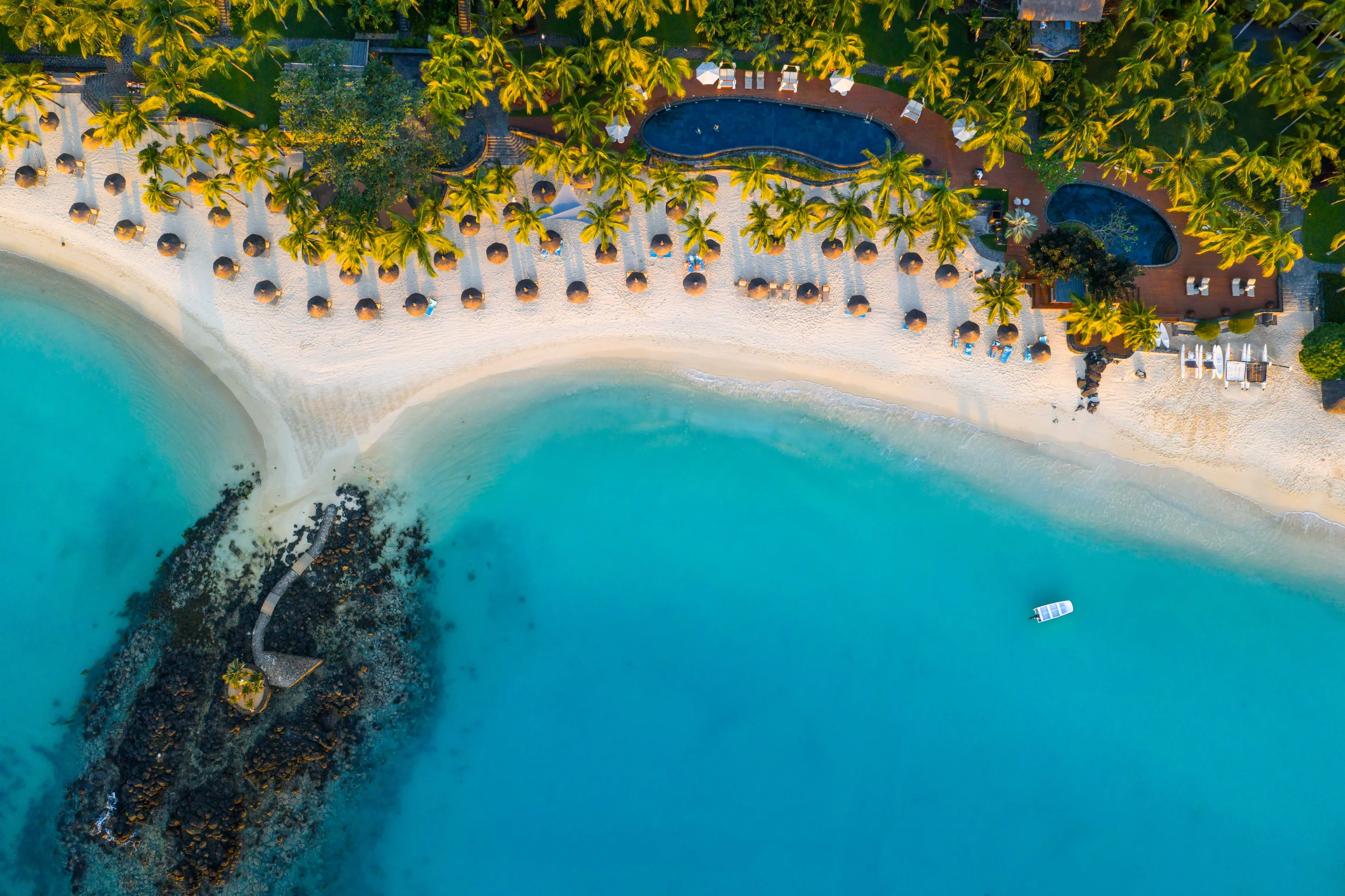 Aerial view of Royal Palm Beachcomber Luxury, its beach curving around a turquoise lagoon