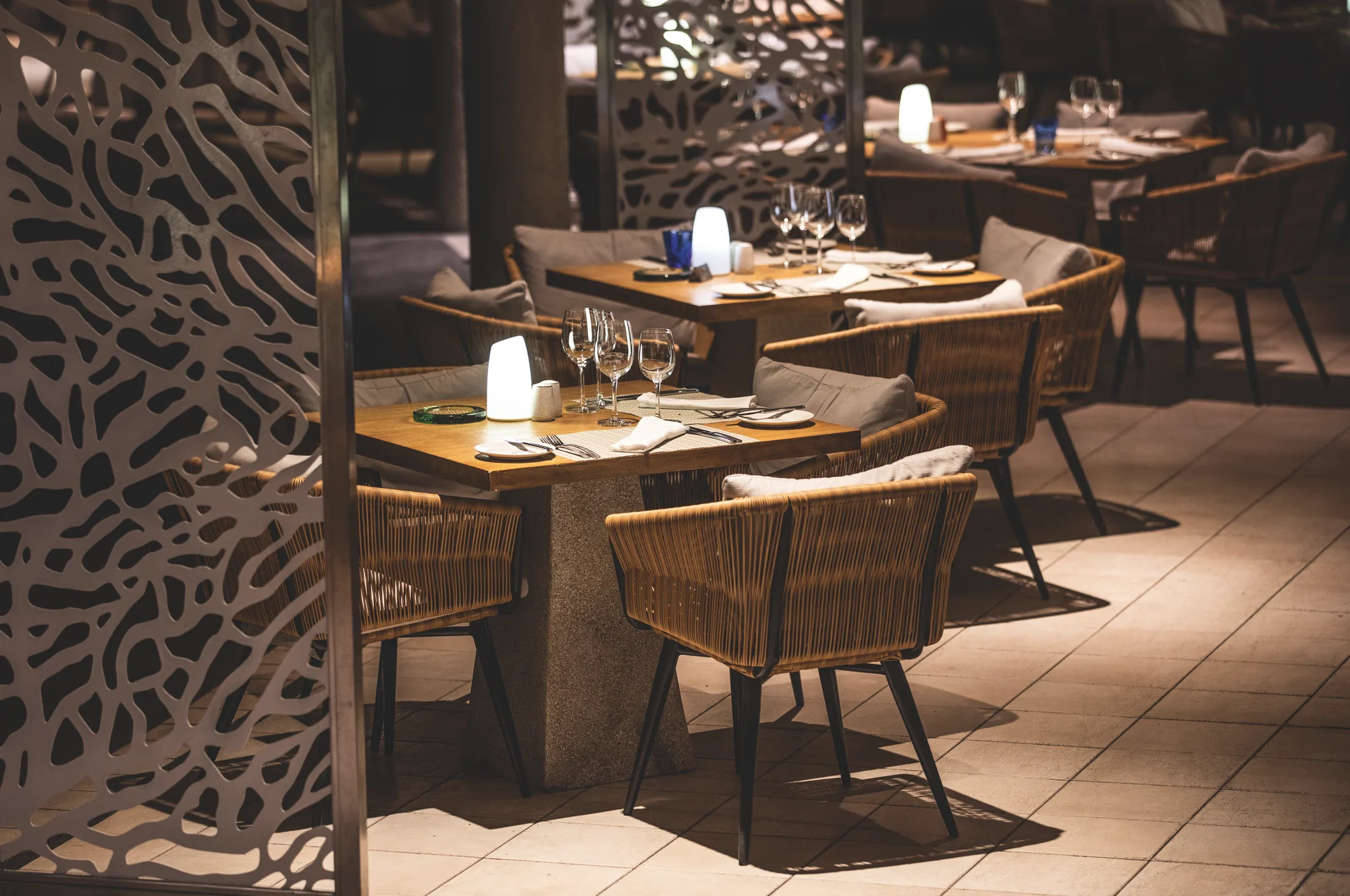Dining tables behind a carved screen in a softly lit restaurant