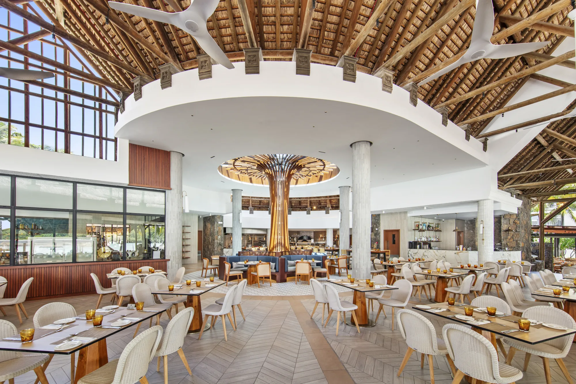 A large restaurant with a timber roof, a sculptural tree centrepiece and rows of tables