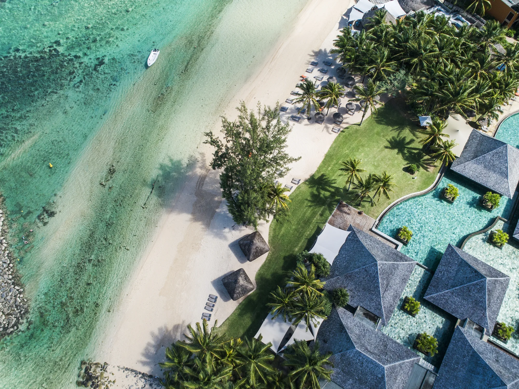 Aerial view of the beach and lagoon beside pool villas with grey roofs