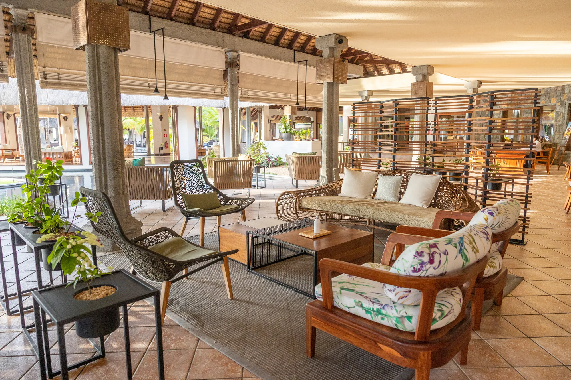 A lounge with patterned armchairs, a sofa and timber screens