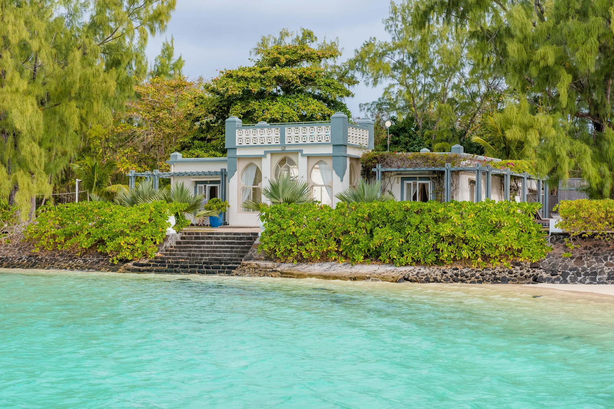 The island's white Moorish-style villa behind a garden, with steps down to the lagoon