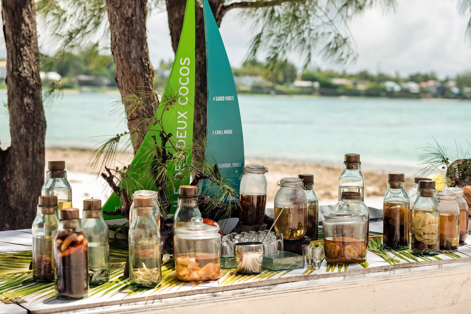 Jars and bottles of flavoured rum set out on a table by the beach