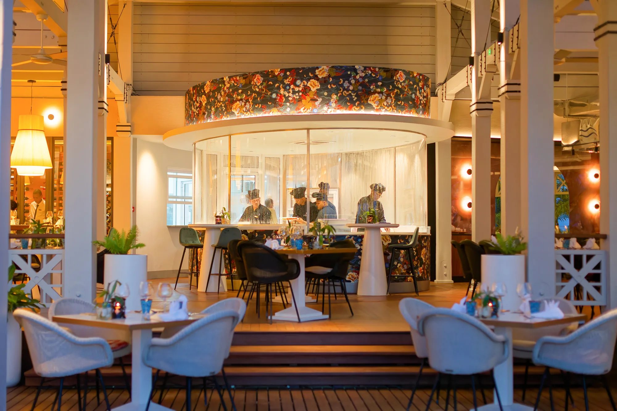 A restaurant with an open kitchen counter, lit in the evening