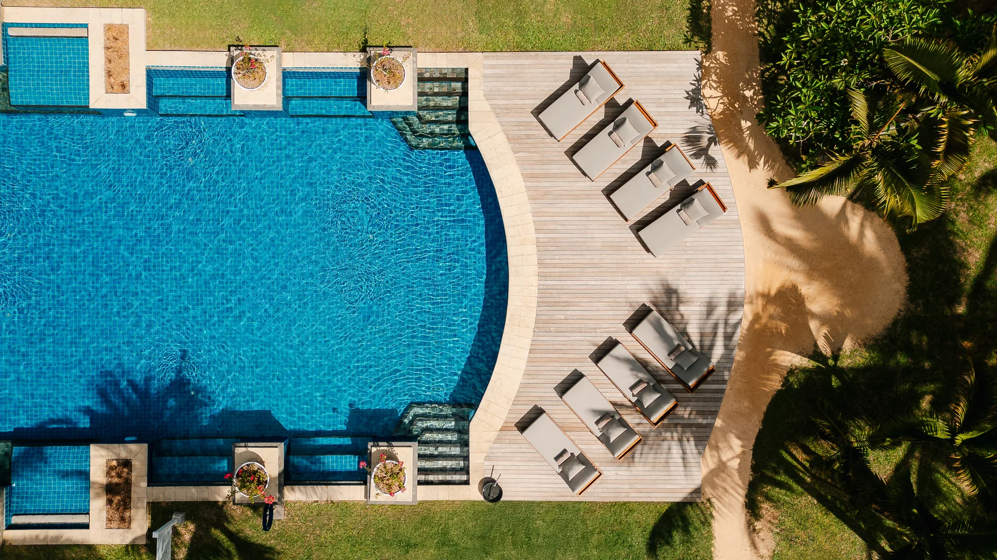 Aerial view of a long pool with a wooden deck and loungers