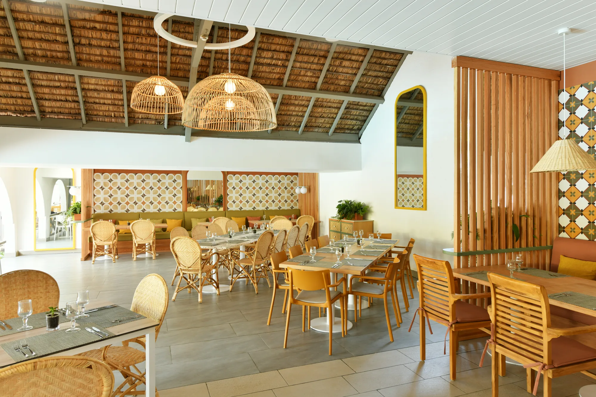 A restaurant with rattan chairs, wooden tables and woven pendant lights