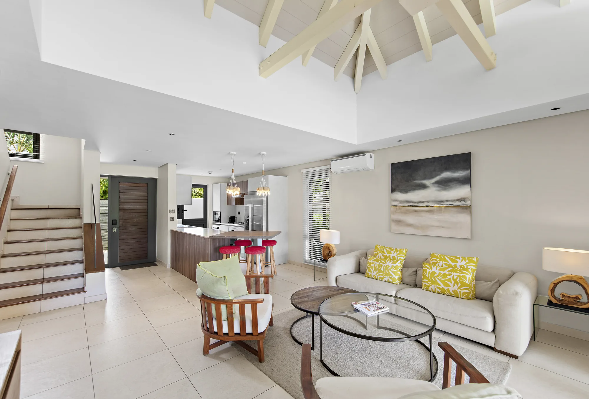 A villa living room with sofas, a staircase and an open kitchen