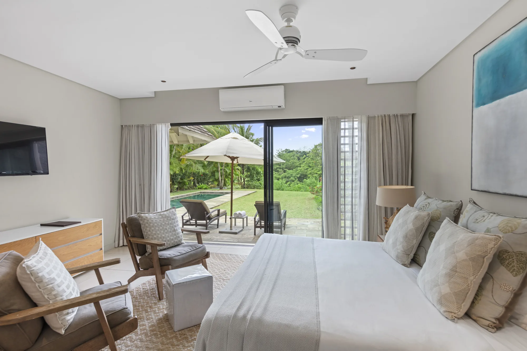 A bedroom with a ceiling fan and doors open to a pool terrace