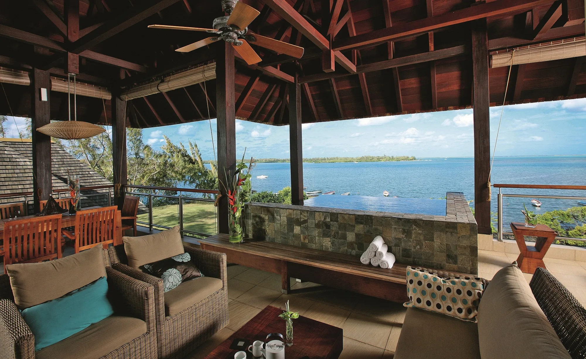 A covered terrace with sofas beside a plunge pool, looking out to sea
