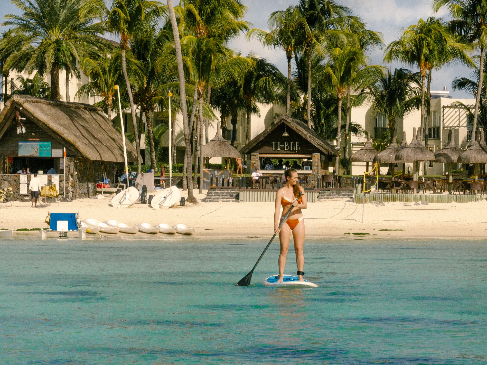 A guest paddleboarding in the lagoon in front of the beach and resort