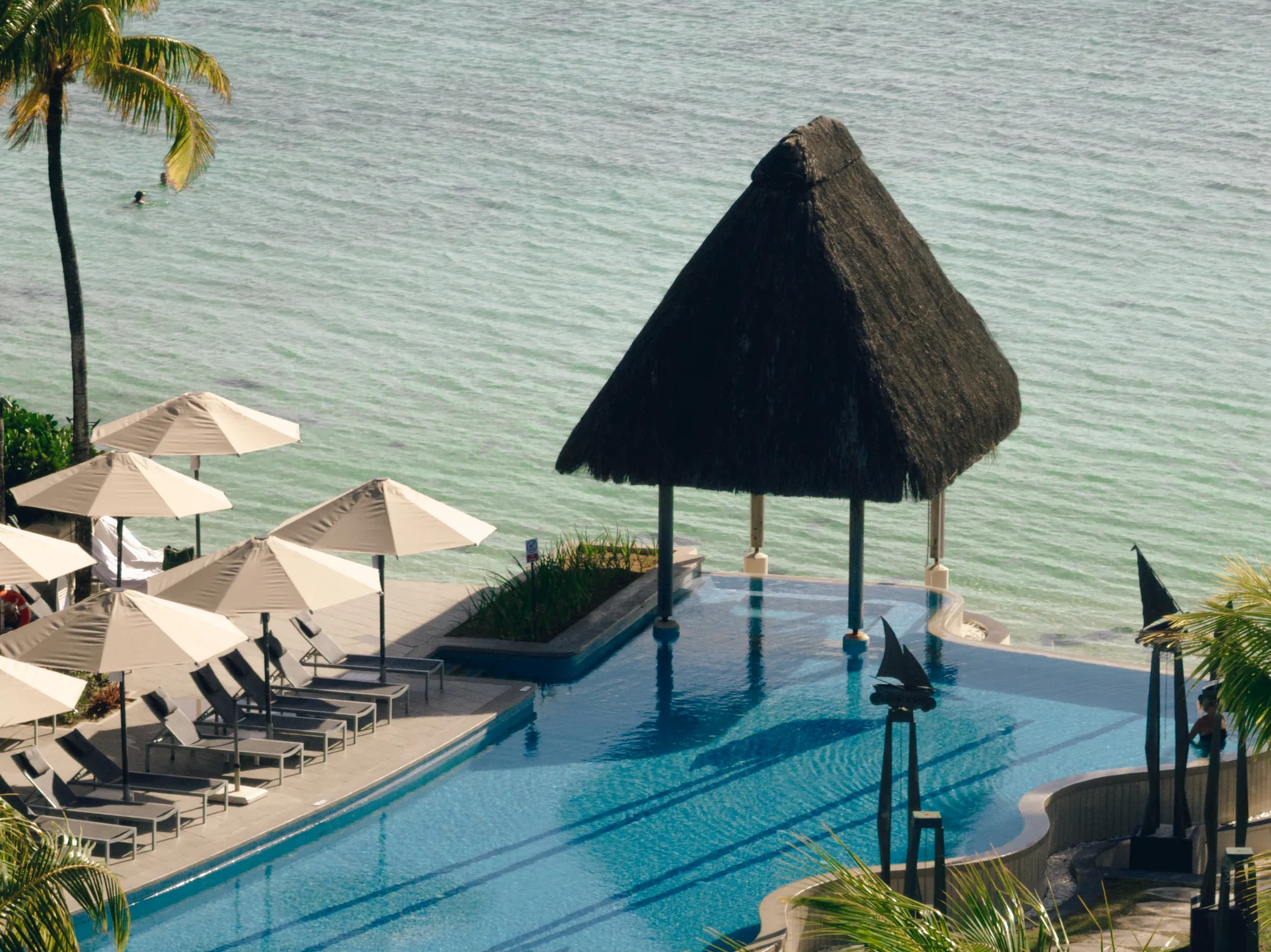 A thatched pavilion over an infinity pool at the edge of the lagoon