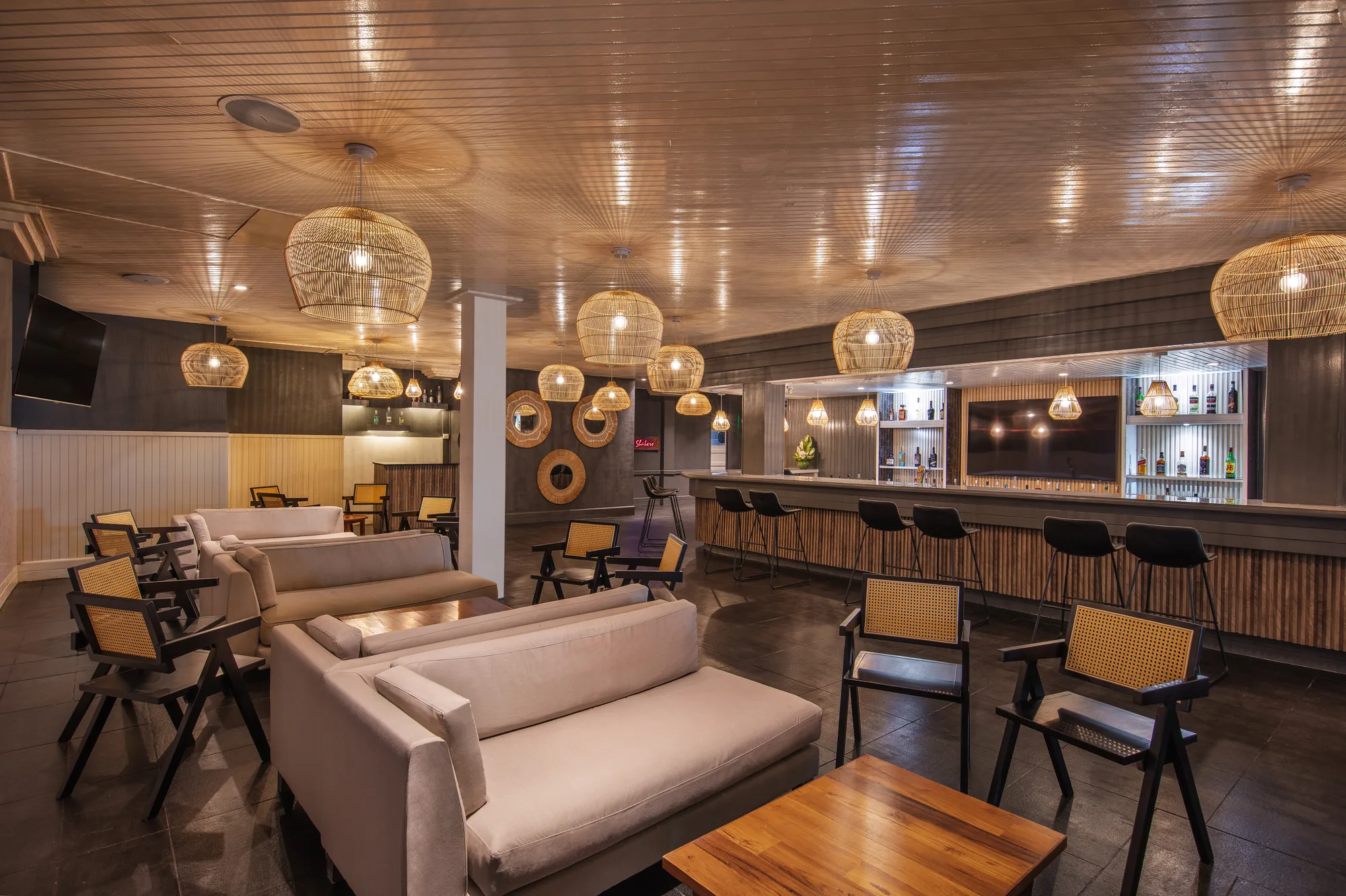 A bar and lounge with sofas and woven pendant lights