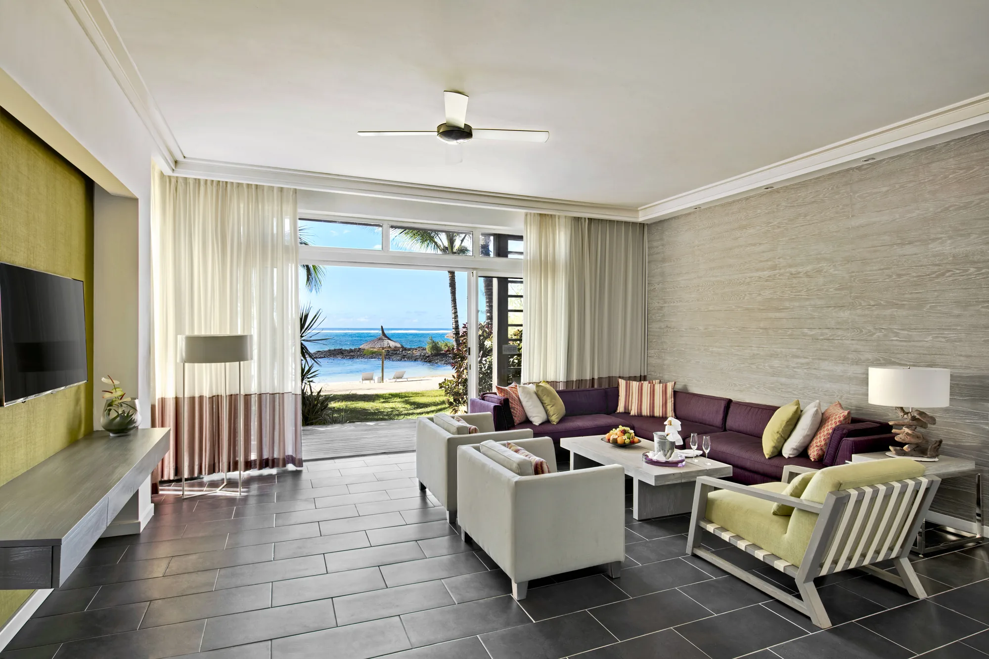 A suite sitting room with sofas, opening onto a terrace and the beach