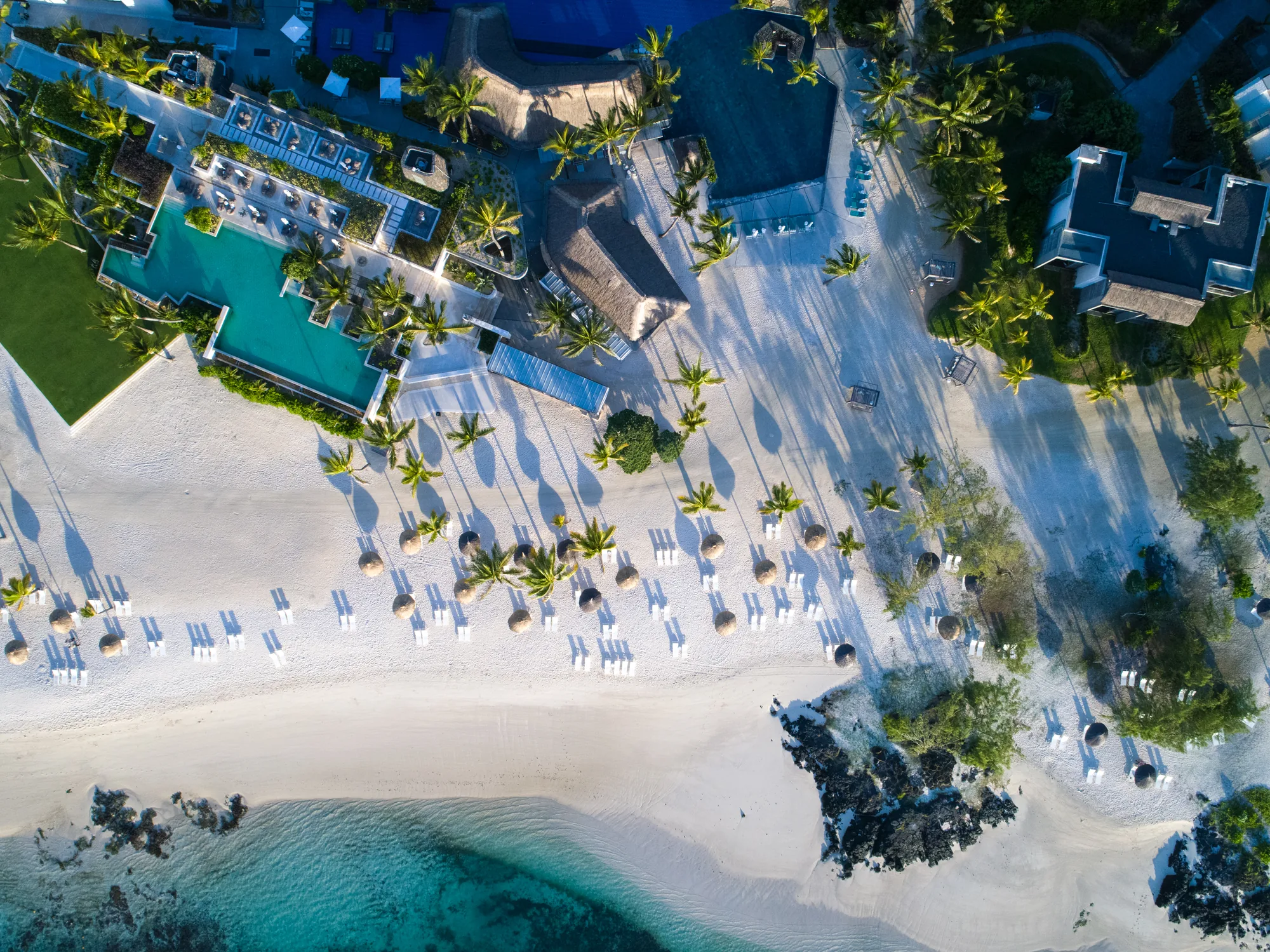 Aerial view of the beach lined with loungers beside the pools and lagoon
