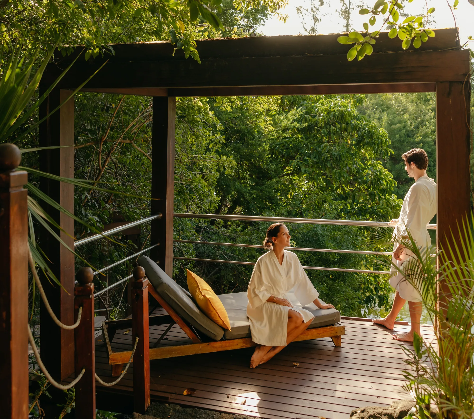 Two guests in robes on a timber deck among the trees