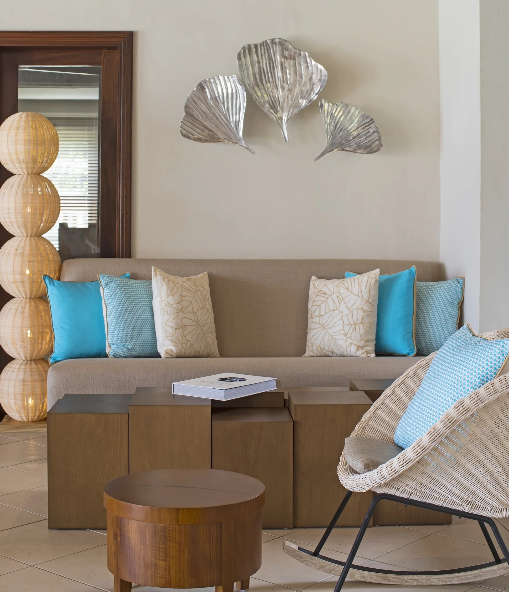 A sofa with turquoise cushions, a rocking chair and a small table