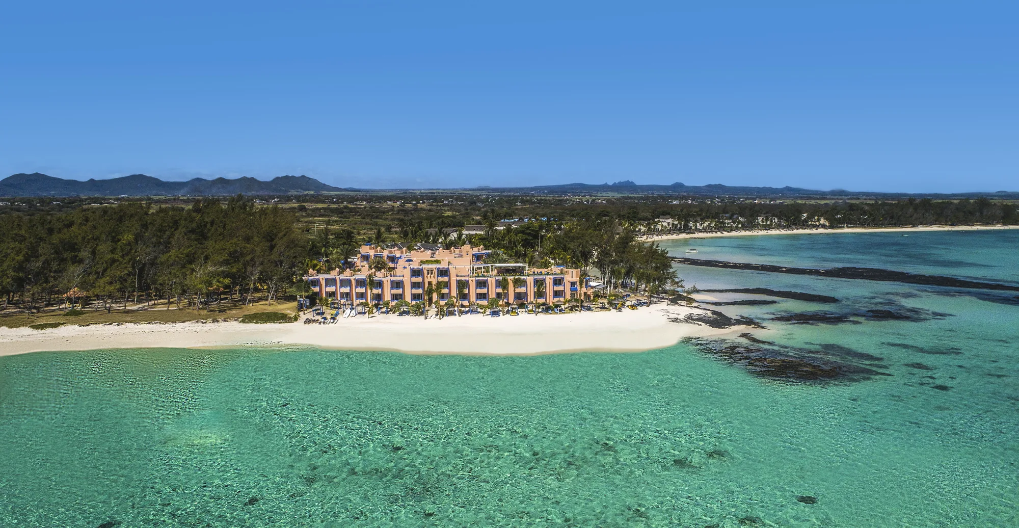 SALT of Palmar from across the lagoon, its pink buildings on the beach with hills behind