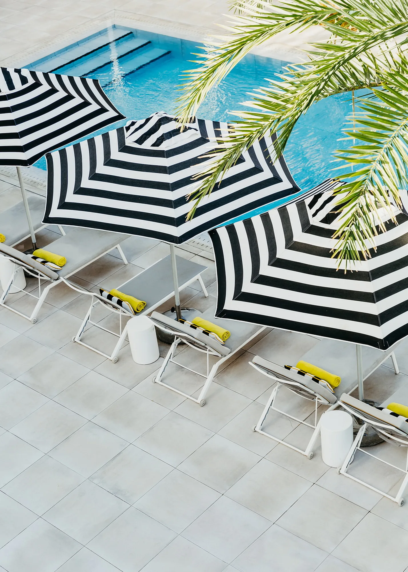 Black and white striped parasols over loungers beside the pool