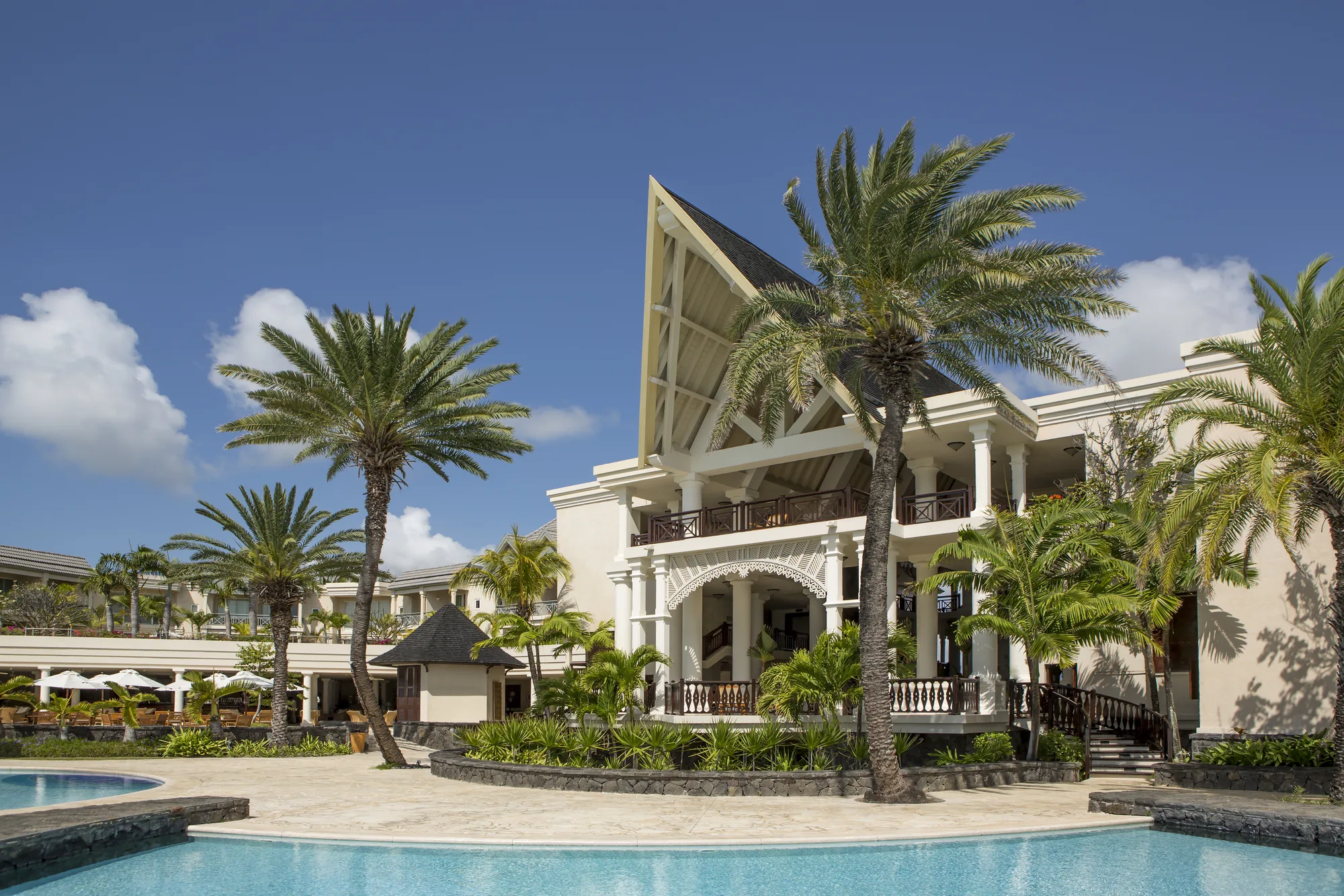 The white colonial-style main building behind palm trees and a pool