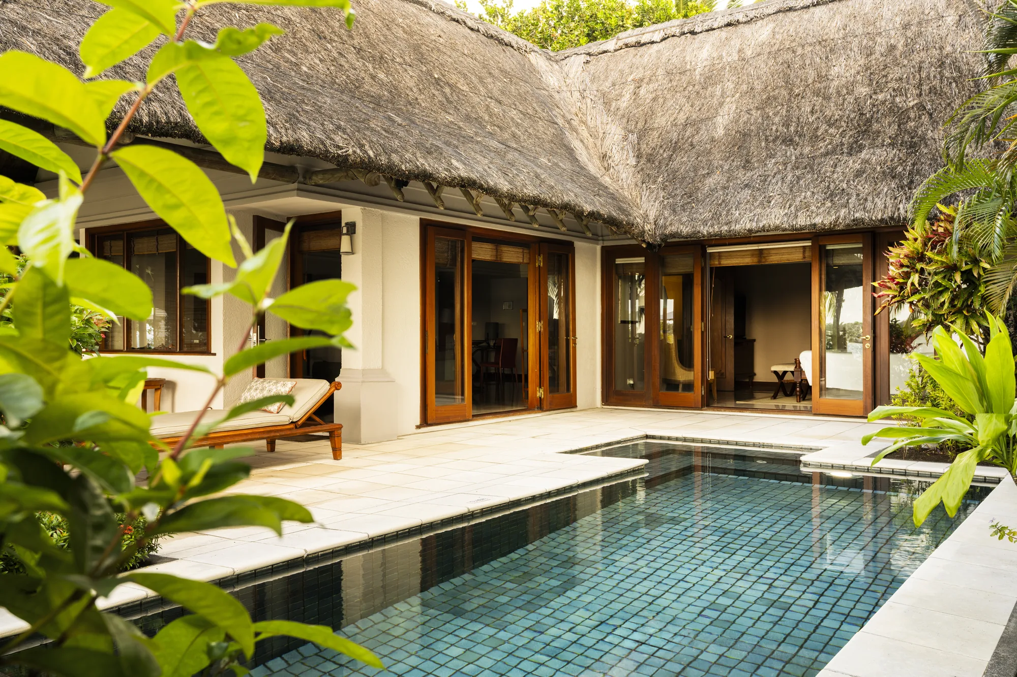 A private pool in a courtyard in front of a thatched villa