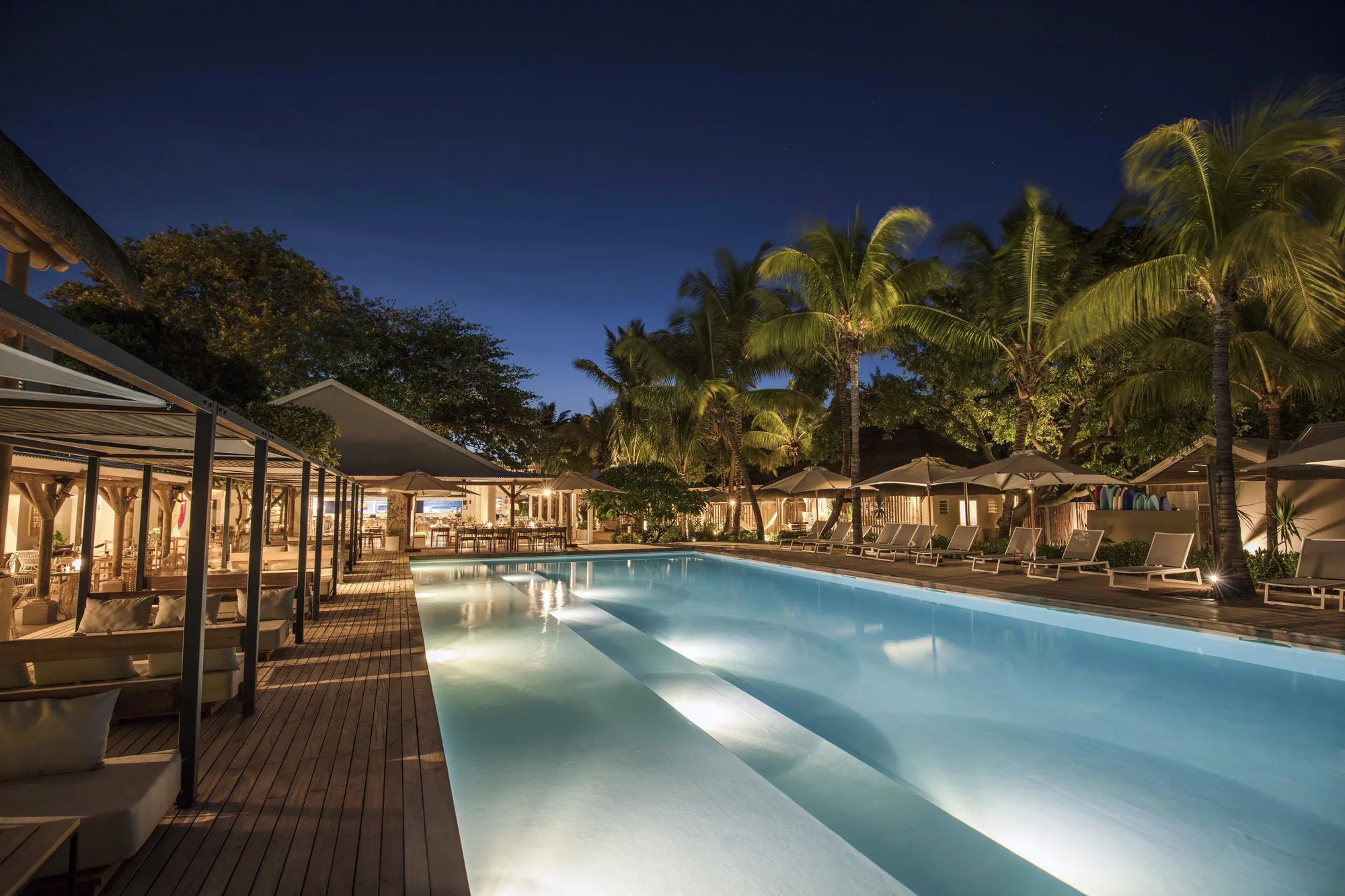 The long pool at Veranda Tamarin at dusk, lined with loungers under palm trees