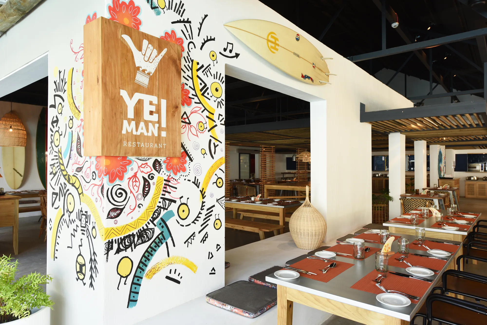 A restaurant with a painted mural wall and long laid tables