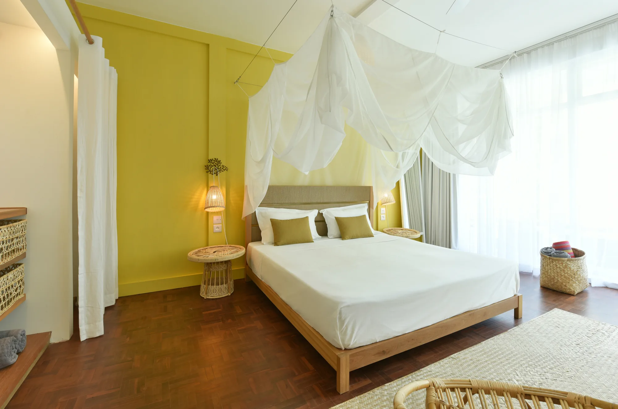 A bedroom with a yellow wall and a white canopy over the bed