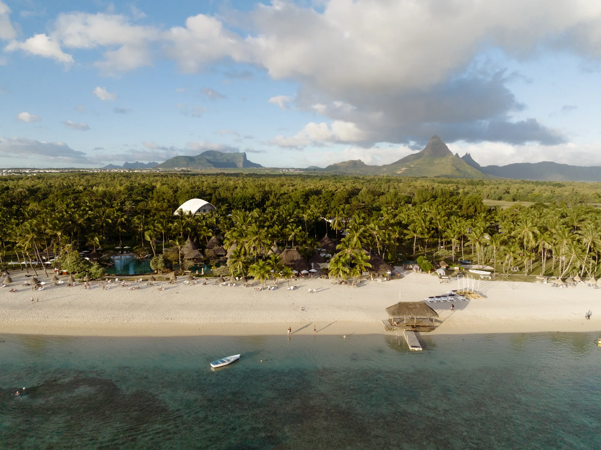 La Pirogue, A Sunlife Resort, behind a long sandy beach with mountains in the distance