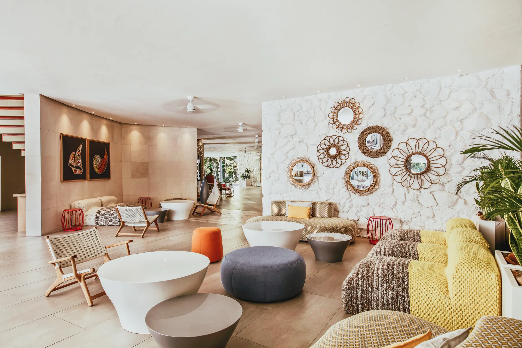 A lounge with rattan wall mirrors, sofas and low round tables