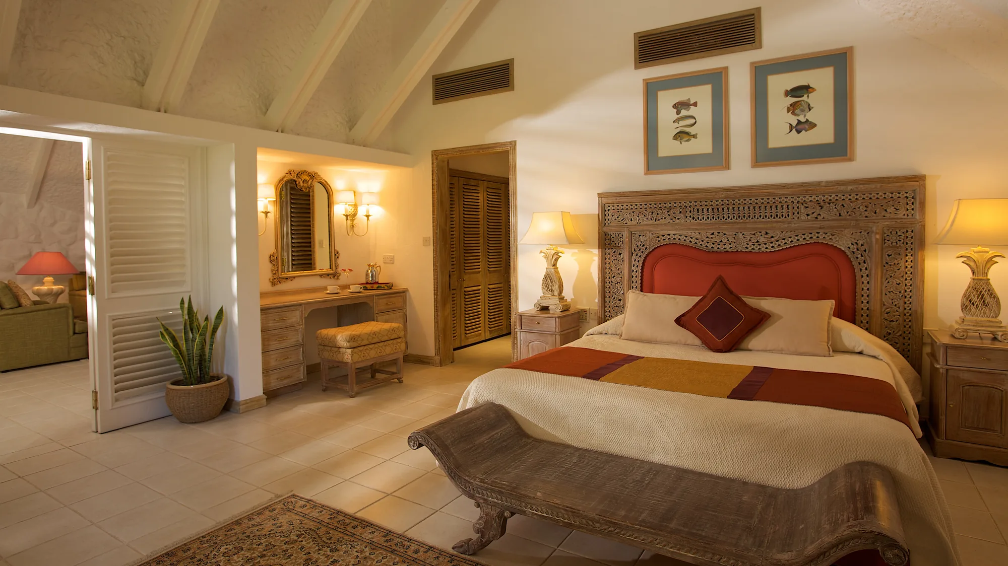 A bedroom with a carved headboard and framed fish prints above the bed