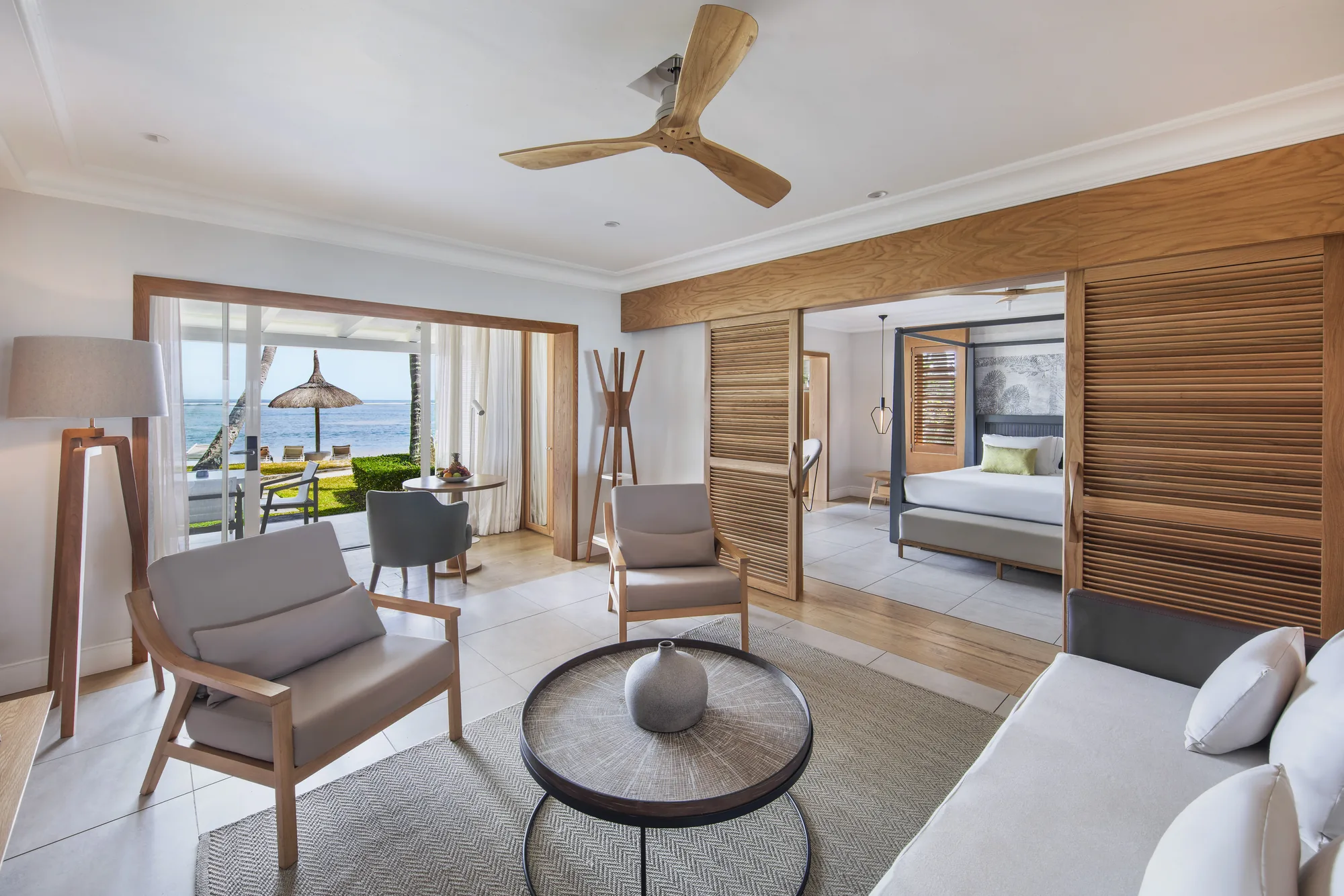 A suite sitting room with a ceiling fan, opening to the bedroom and the sea
