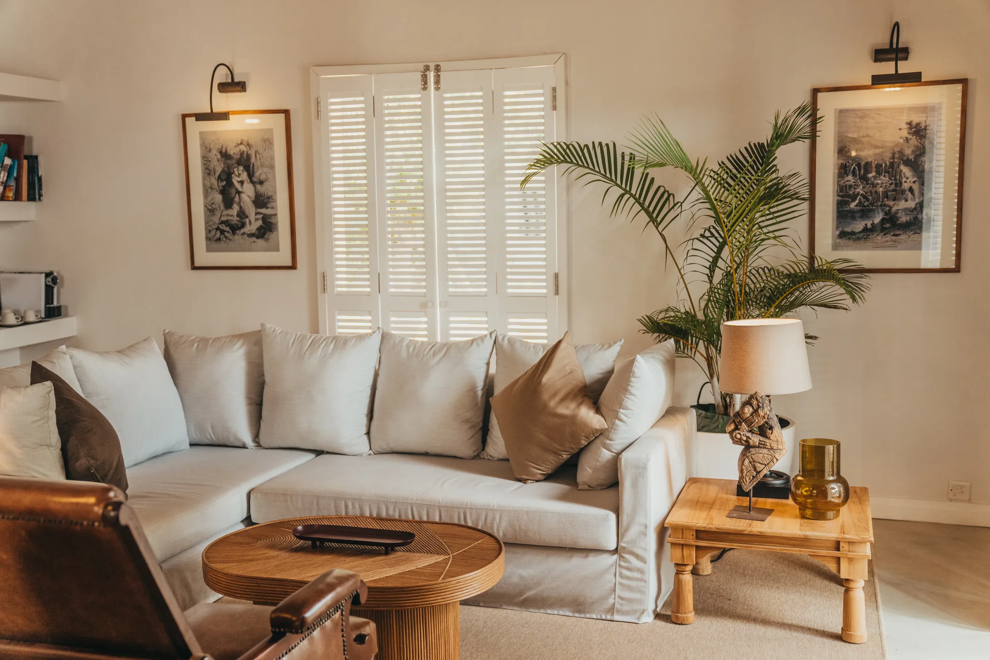 A sitting room with a white sofa, a round table and framed prints