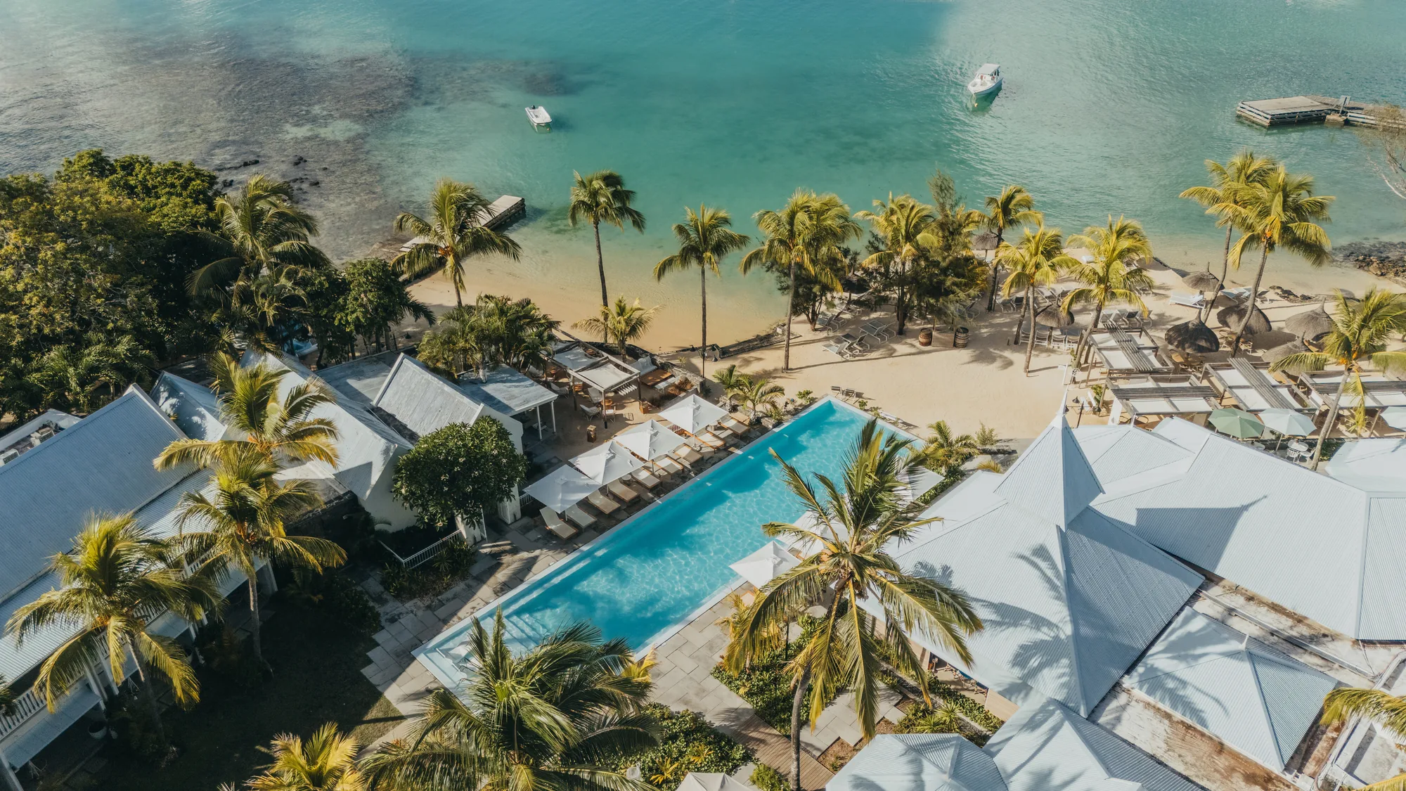 Aerial view of Veranda Grand Baie, its pool and grey roofs beside the beach and bay
