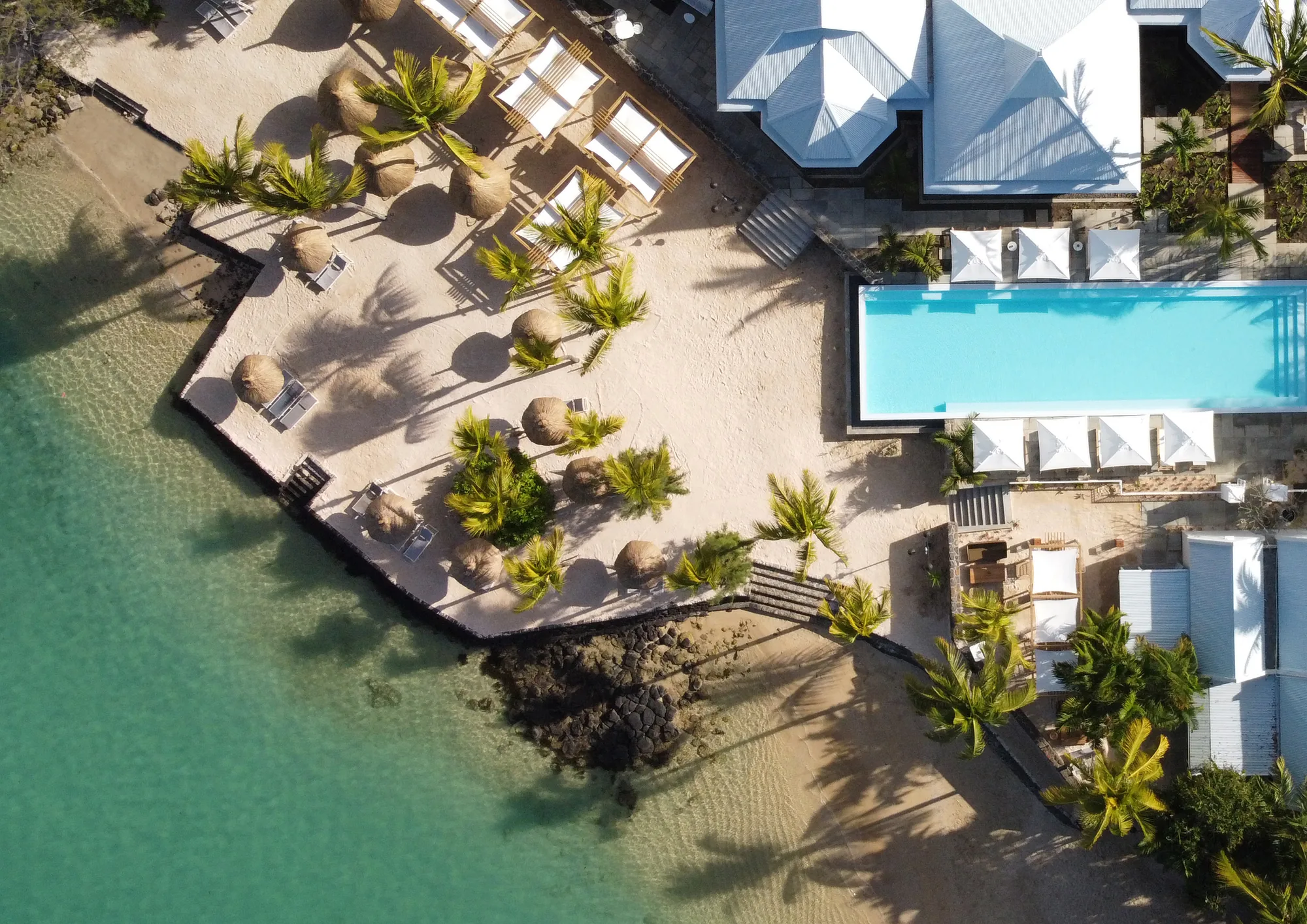 Aerial view of the beach, loungers and a pool beside the lagoon